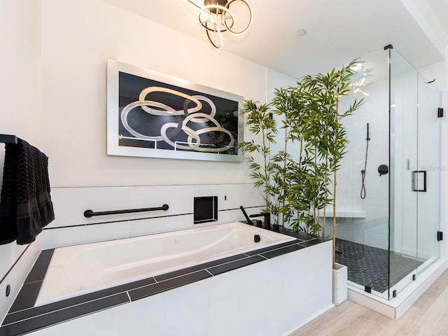 bathroom with an inviting chandelier, wood-type flooring, and shower with separate bathtub