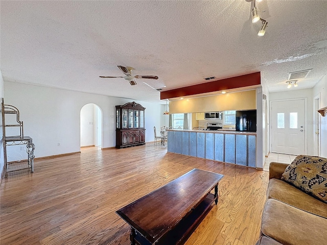 living room featuring ceiling fan, a textured ceiling, and light hardwood / wood-style flooring