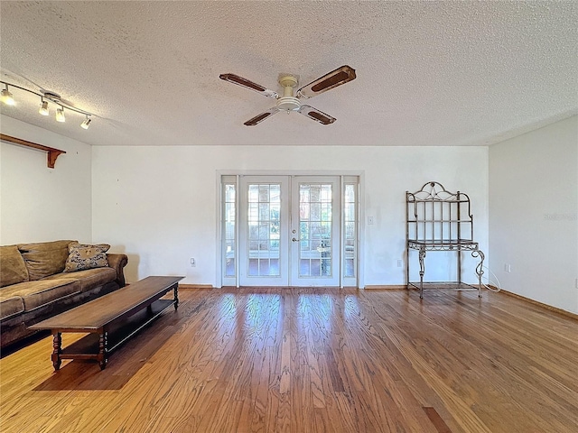 living room featuring hardwood / wood-style floors, ceiling fan, a textured ceiling, and french doors