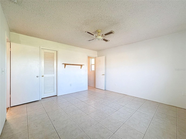 unfurnished bedroom with light tile patterned floors, a textured ceiling, a closet, and ceiling fan