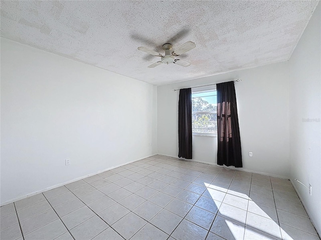 spare room featuring ceiling fan, light tile patterned floors, and a textured ceiling