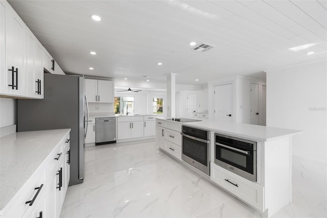 kitchen with ceiling fan, sink, white cabinets, a kitchen island, and appliances with stainless steel finishes