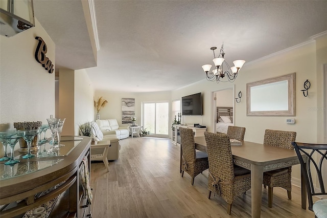 dining area featuring light hardwood / wood-style flooring, ornamental molding, and an inviting chandelier