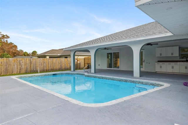 view of pool with an outdoor kitchen, ceiling fan, and a patio area