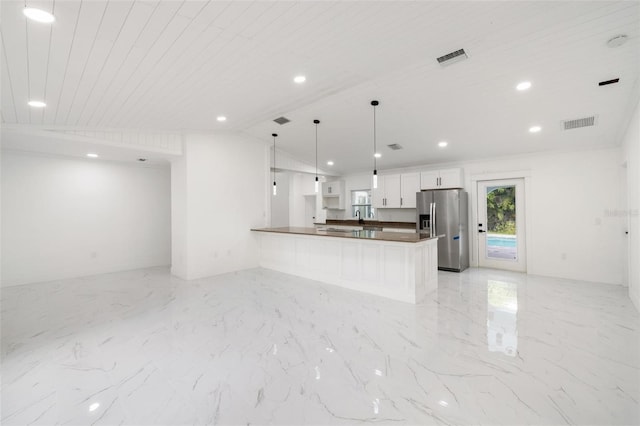 kitchen featuring hanging light fixtures, stainless steel fridge, vaulted ceiling, white cabinets, and wood ceiling