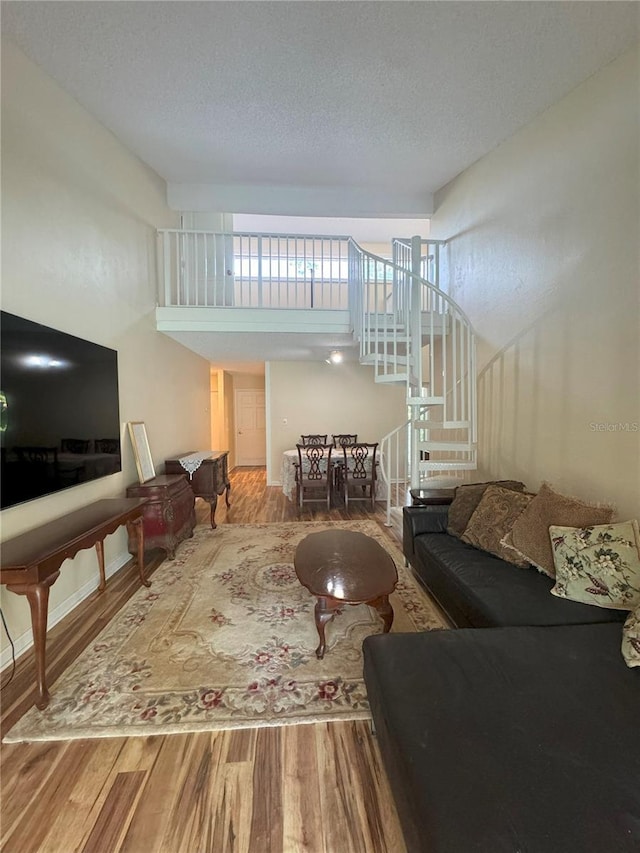 living room featuring hardwood / wood-style floors, a towering ceiling, and a textured ceiling