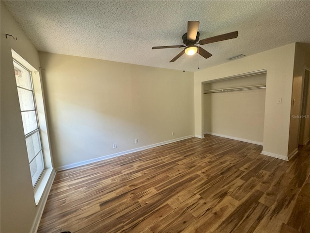 unfurnished bedroom with a textured ceiling, a closet, ceiling fan, and dark wood-type flooring