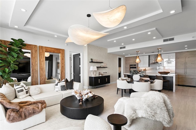 living room featuring light wood-type flooring and a tray ceiling