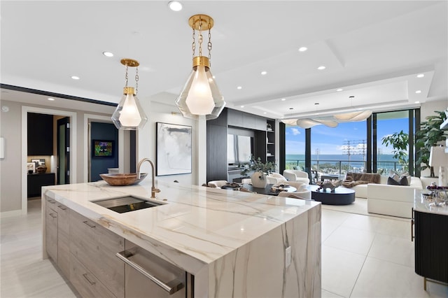 kitchen with pendant lighting, a spacious island, light stone countertops, and sink