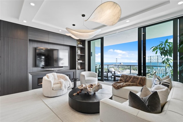 living room featuring a raised ceiling, built in features, and expansive windows