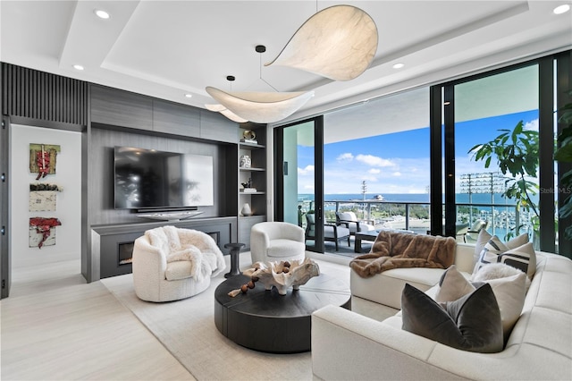 living room with built in features, a wall of windows, and a tray ceiling