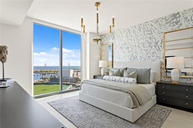 bedroom with a water view, expansive windows, and a notable chandelier