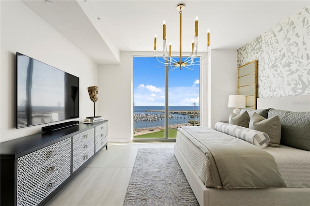 bedroom with expansive windows, a water view, multiple windows, and a notable chandelier