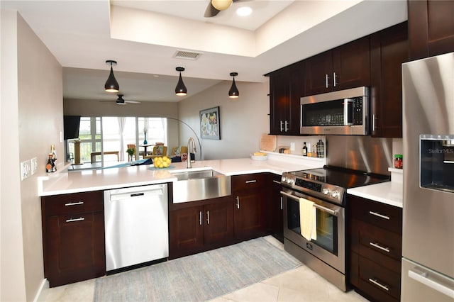 kitchen featuring kitchen peninsula, stainless steel appliances, ceiling fan, sink, and decorative light fixtures