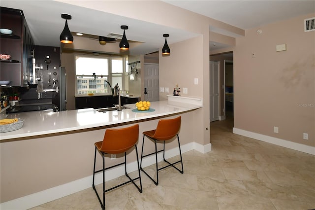 kitchen featuring a breakfast bar, sink, stainless steel fridge, dark brown cabinets, and kitchen peninsula