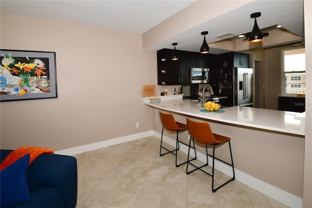 kitchen with a breakfast bar, hanging light fixtures, sink, appliances with stainless steel finishes, and kitchen peninsula