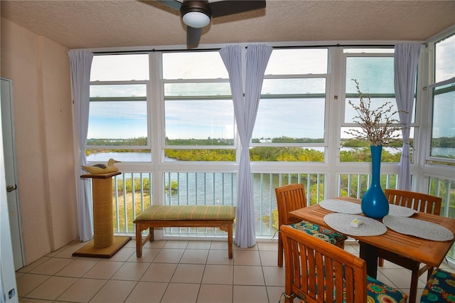 sunroom featuring ceiling fan and a water view