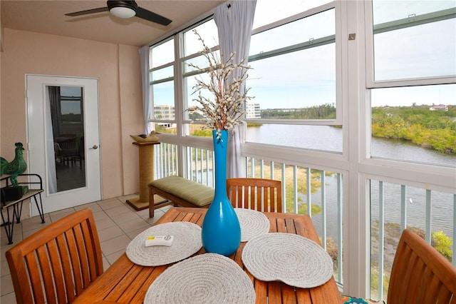 sunroom with ceiling fan and a water view