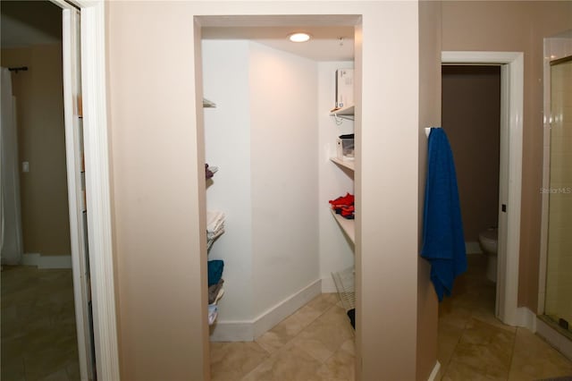 bathroom with tile patterned floors, a shower with door, and toilet