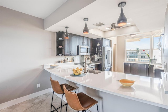 kitchen featuring appliances with stainless steel finishes, kitchen peninsula, hanging light fixtures, and a breakfast bar area