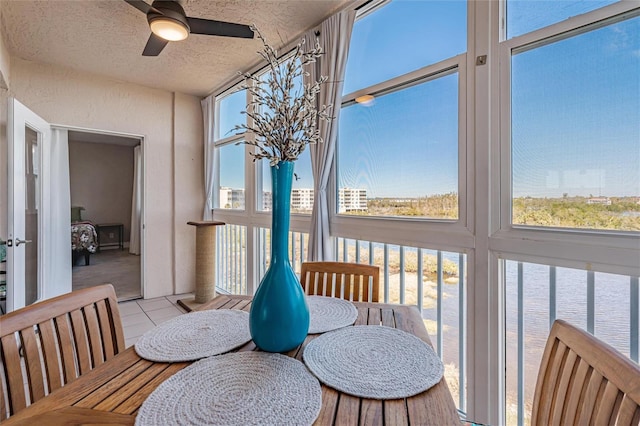 sunroom with a water view, a healthy amount of sunlight, and ceiling fan