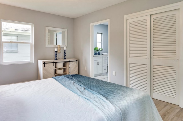 bedroom featuring light hardwood / wood-style floors, a closet, and ensuite bath