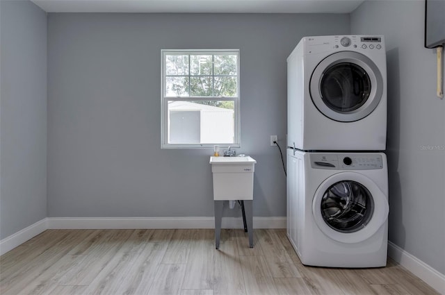 laundry area with light hardwood / wood-style floors and stacked washer / dryer