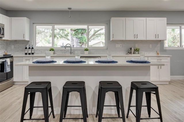 kitchen featuring a center island, stainless steel appliances, white cabinetry, and a breakfast bar area