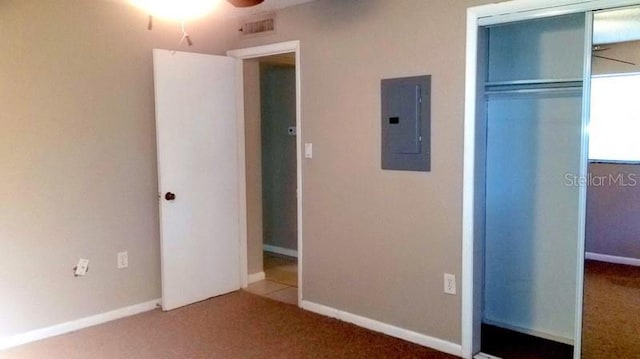 unfurnished bedroom featuring electric panel, carpet floors, and a closet