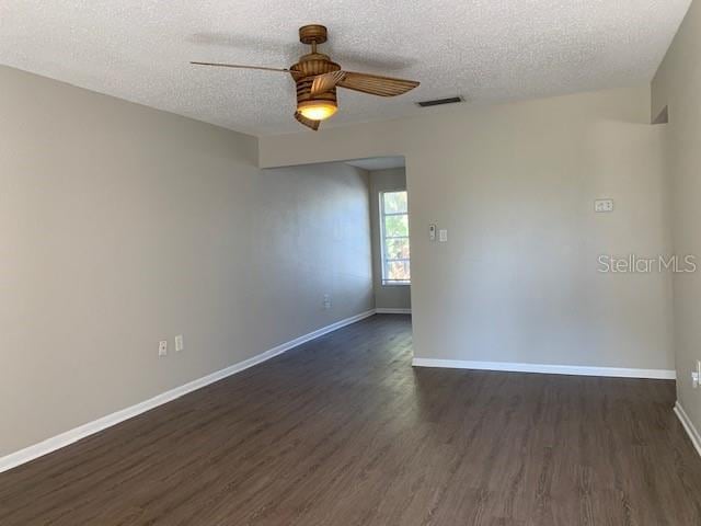 unfurnished room featuring dark hardwood / wood-style flooring, a textured ceiling, and ceiling fan