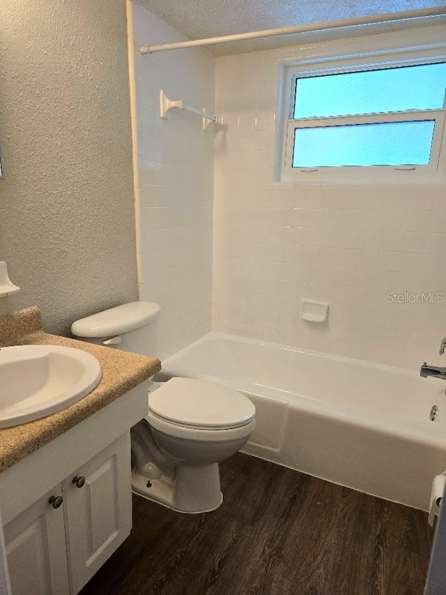 full bathroom featuring wood-type flooring, toilet, tiled shower / bath combo, and vanity