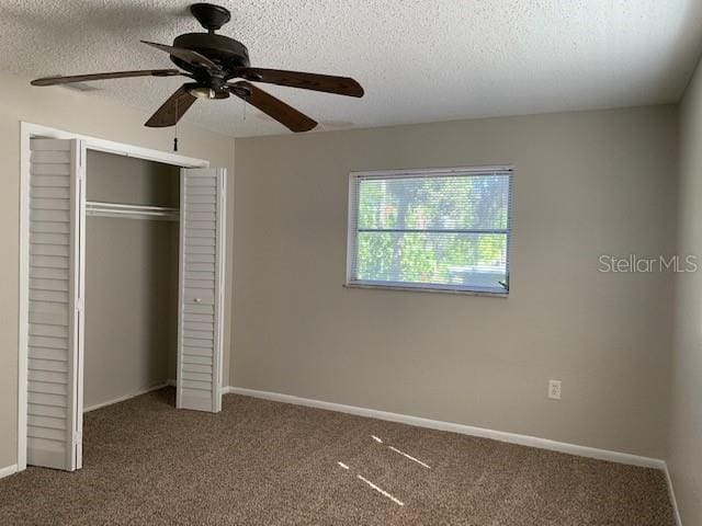 unfurnished bedroom featuring ceiling fan, a closet, a textured ceiling, and carpet