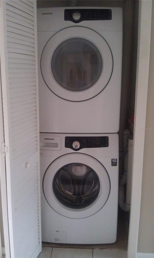 laundry room featuring stacked washer / dryer and light tile patterned floors