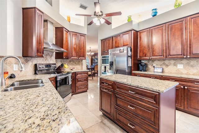 kitchen with decorative backsplash, light stone counters, stainless steel appliances, wall chimney range hood, and sink