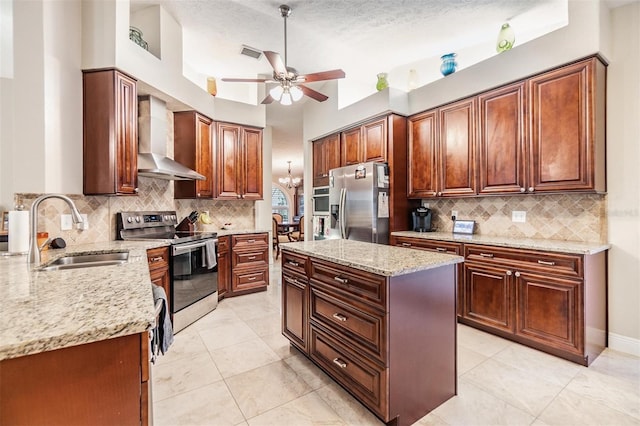 kitchen featuring light stone countertops, sink, wall chimney exhaust hood, stainless steel appliances, and a kitchen island