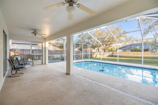 view of pool featuring glass enclosure, ceiling fan, and a patio area