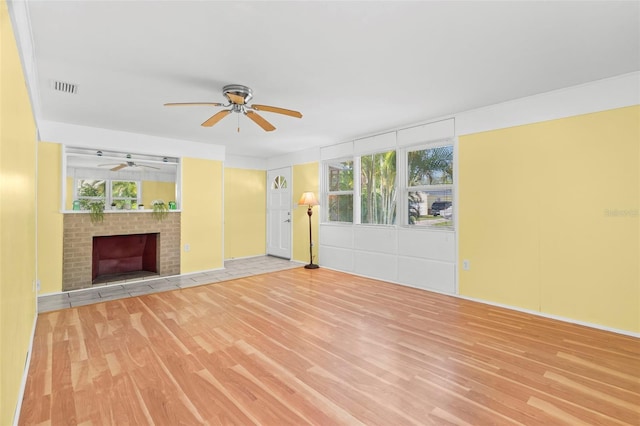 unfurnished living room featuring a brick fireplace and light hardwood / wood-style flooring