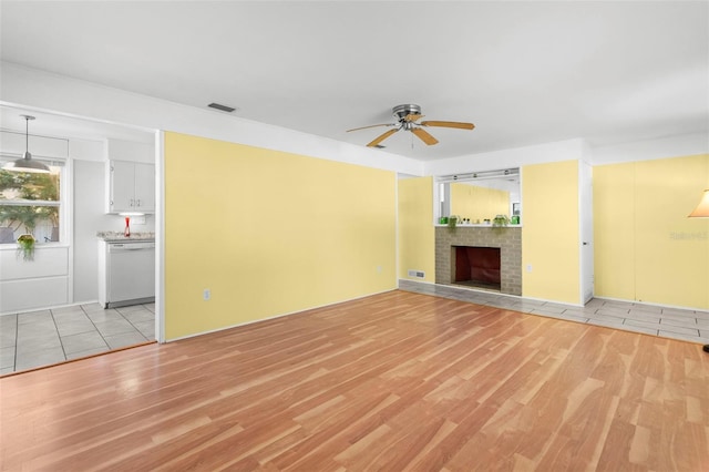 unfurnished living room with ceiling fan, a fireplace, and light hardwood / wood-style flooring