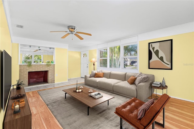 living room with a fireplace, light hardwood / wood-style floors, ceiling fan, and plenty of natural light