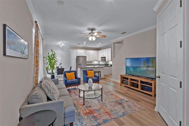 living room with light hardwood / wood-style floors, ceiling fan, and crown molding