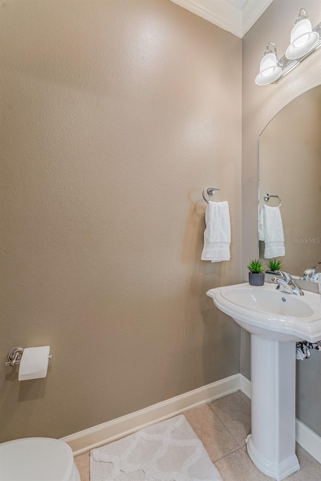 bathroom featuring toilet, tile patterned floors, ornamental molding, and sink