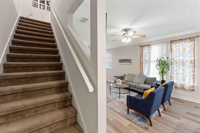 stairs with hardwood / wood-style flooring, ceiling fan, and ornamental molding