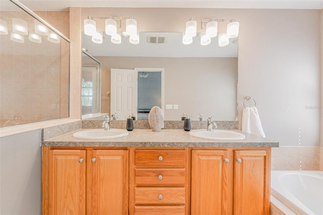 bathroom with tiled tub and vanity