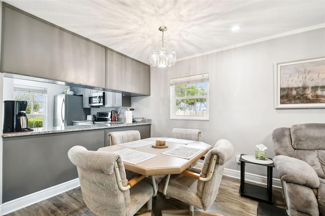 dining space with a chandelier, light hardwood / wood-style flooring, plenty of natural light, and crown molding