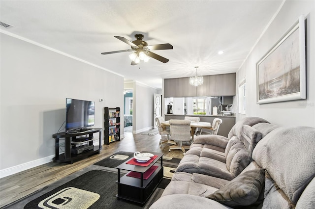 living room with ceiling fan with notable chandelier, hardwood / wood-style flooring, and ornamental molding