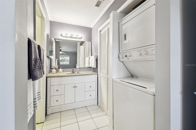 bathroom featuring tile patterned flooring, vanity, ceiling fan, and stacked washer / dryer