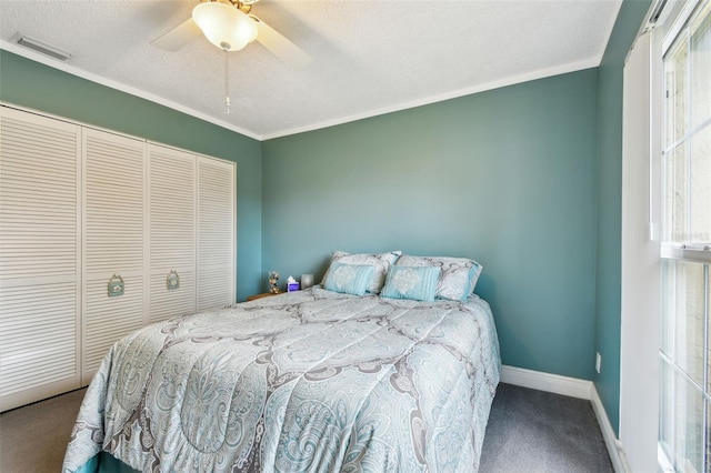 bedroom with a textured ceiling, ceiling fan, multiple windows, carpet floors, and a closet