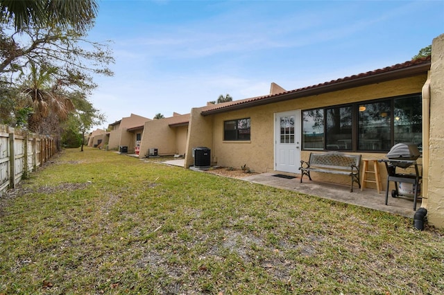 rear view of property featuring a lawn and central AC unit