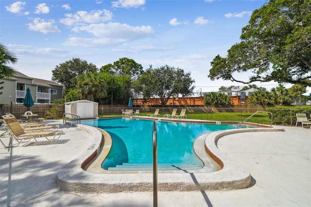 view of pool featuring a patio and a storage unit