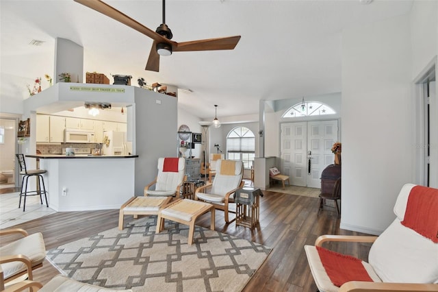 living room with ceiling fan, dark hardwood / wood-style floors, and vaulted ceiling